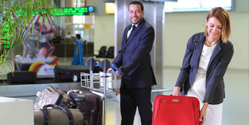 Female in business class wearing headphones looking at the screen in front of her with an open-mouthed smile